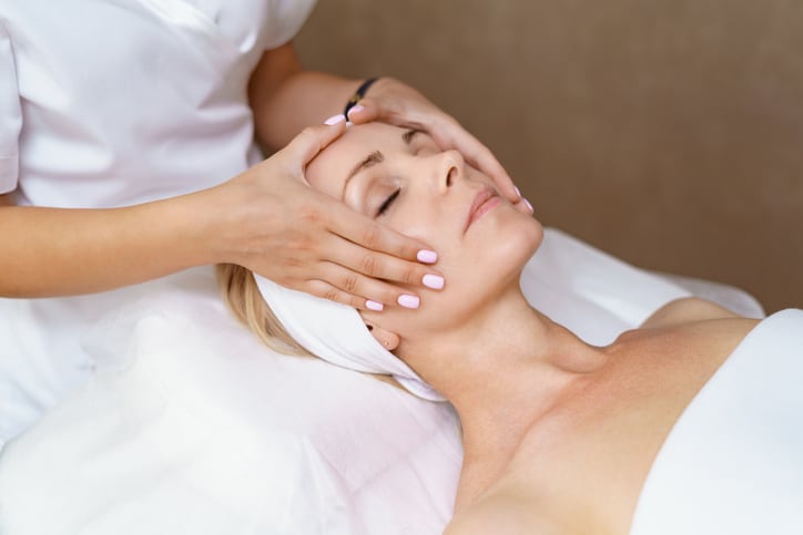 Woman receiving a facial treatment from a spa therapist after spa therapy