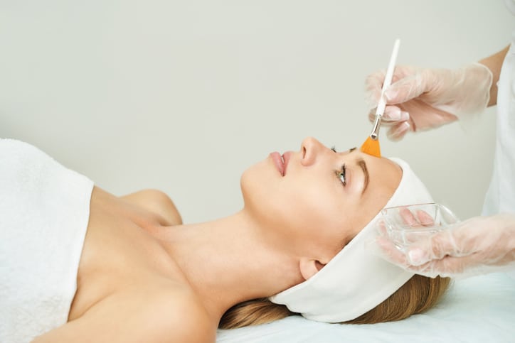 Spa therapy graduate conducts a chemical peel treatment rejuvenating a client's skin.