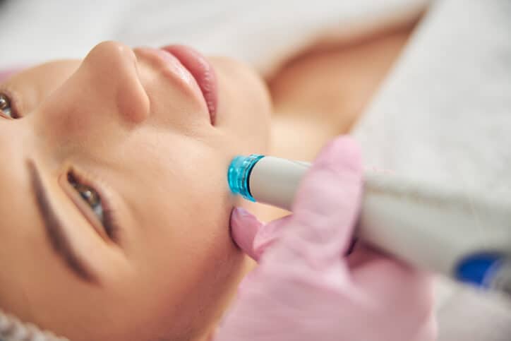 Aesthetician performing hydradermabrasion on a client after receiving her certification
