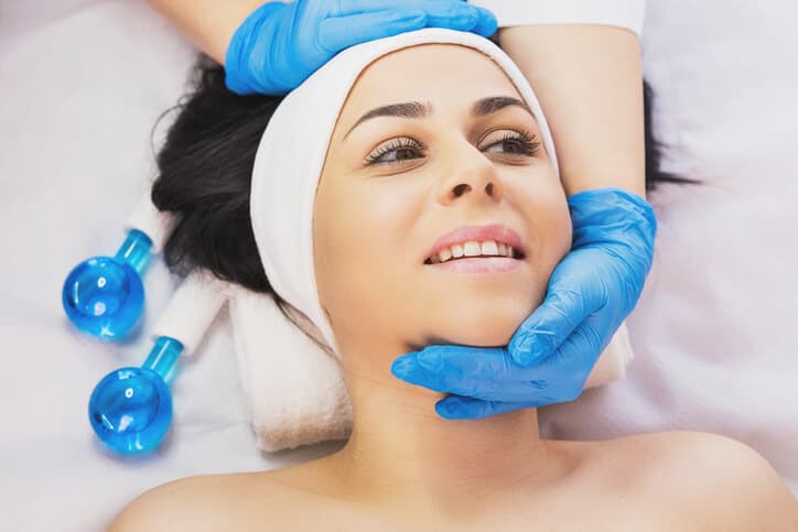 Happy woman receiving a facial treatment from a certified medical aesthetician
