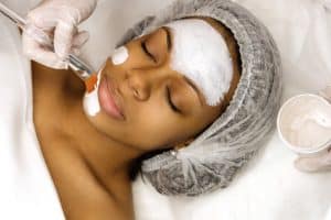 Woman receiving a facial mask during a facial from a medical aesthetician.